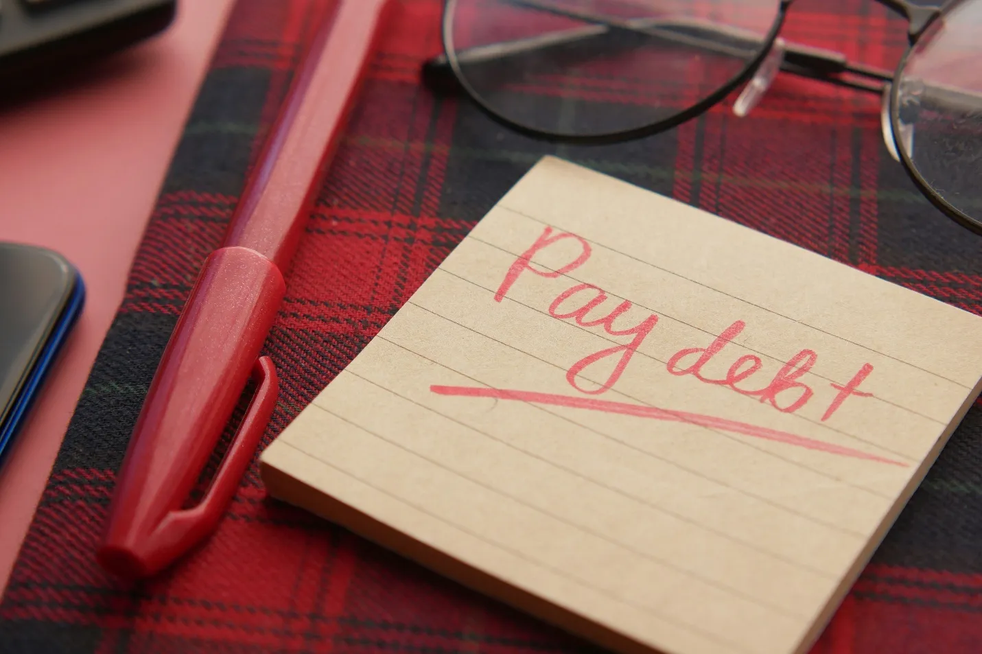 Person planning debt payoff strategy with a calculator and financial statements