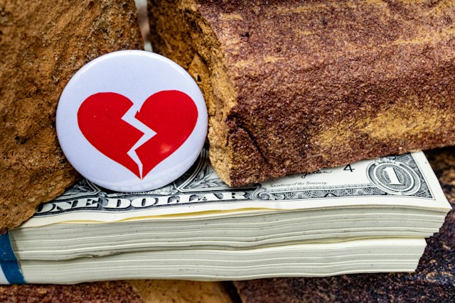 Broken heart token resting on cash, representing post-divorce financial choices