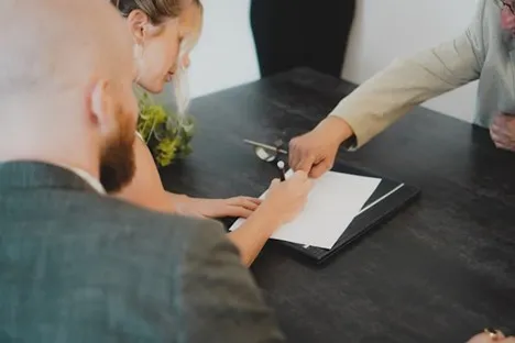 People reviewing and signing settlement documents at a table