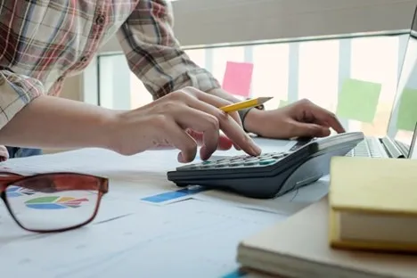 Person using calculator to evaluate financial documents