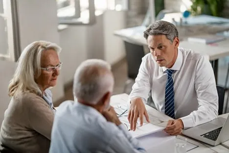 Financial advisor discussing annuity options with older couple in modern office