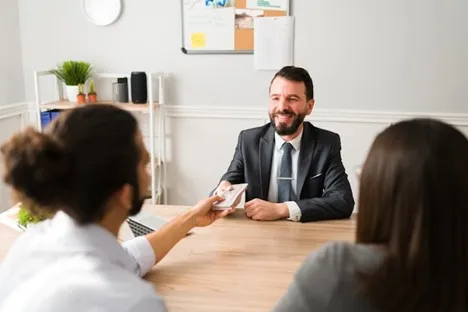 Financial advisor handing cash to a couple across a desk