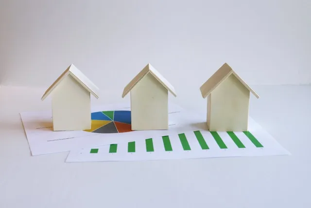 Model house and keys on financial documents representing real estate investment