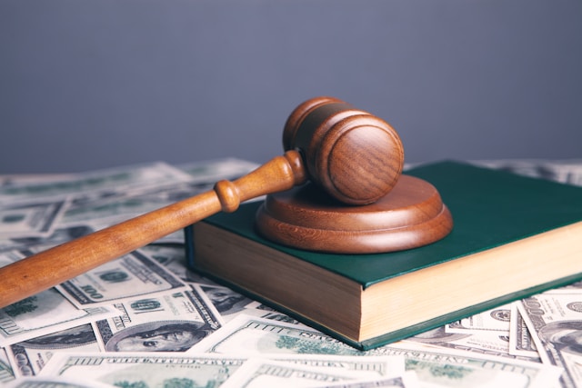 Judge’s gavel on a law book with currency beneath it