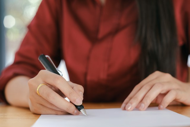Person writing on a document at a desk