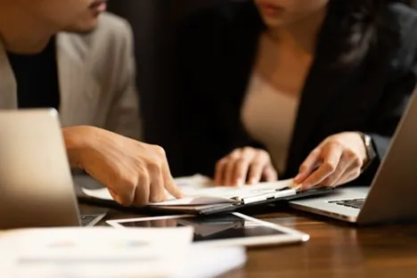 Couple reviewing settlement paperwork with laptops at a desk